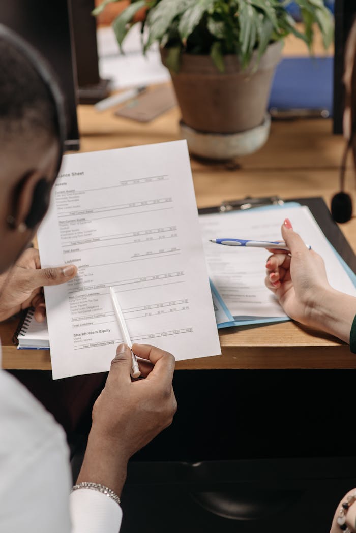 Two professionals reviewing financial documents and discussing strategy in an office environment.