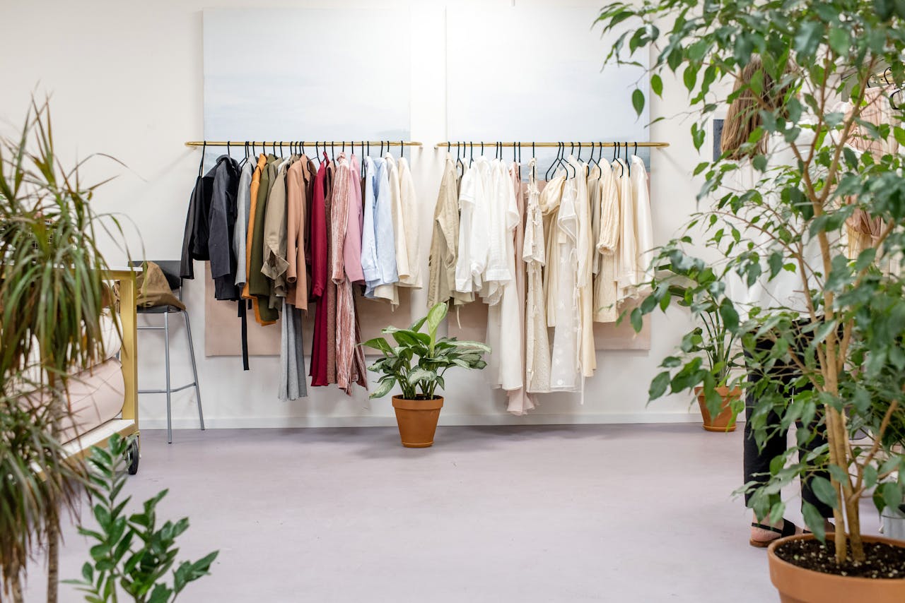 heros-img Chic fashion boutique showcasing vibrant clothing collection with lush indoor plants.