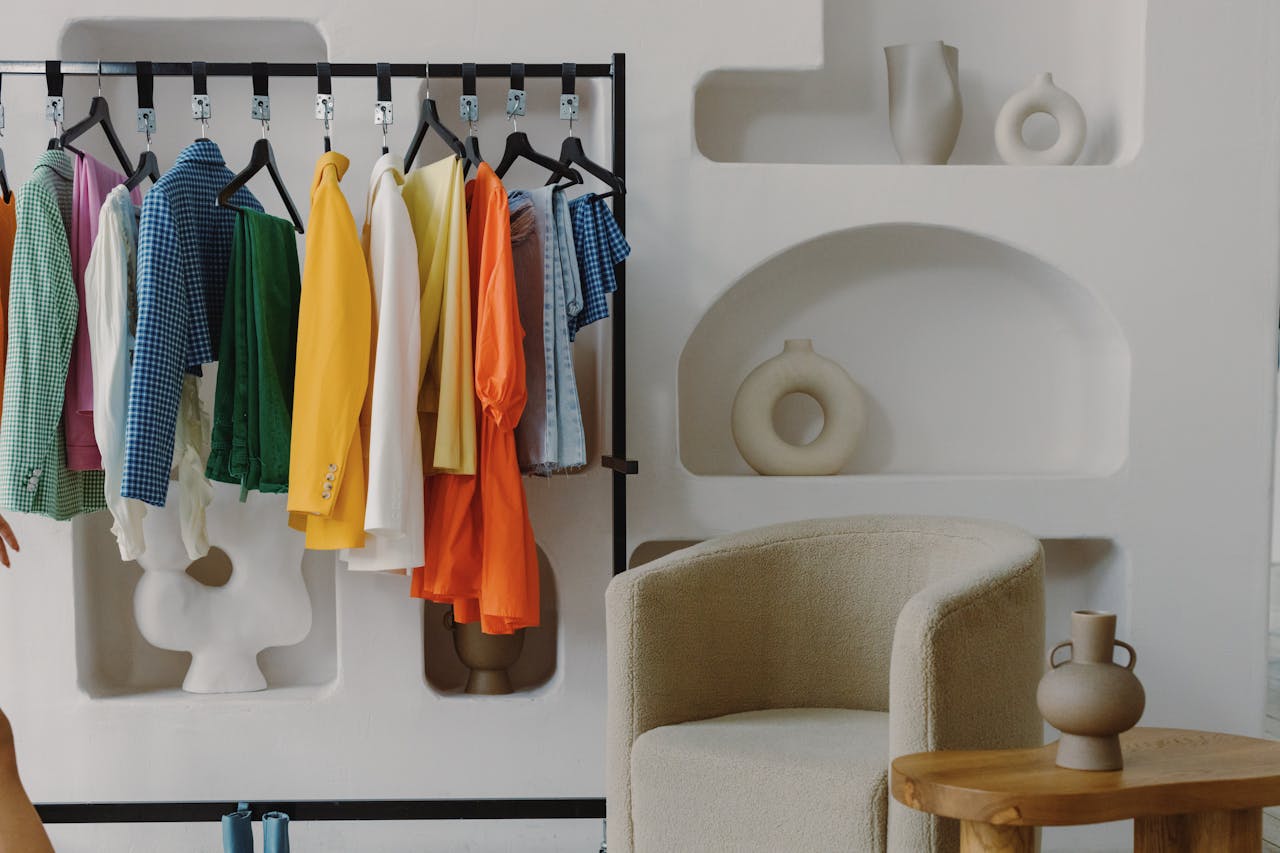 about-us A colorful variety of clothes hanging on a rack inside a contemporary room with artistic decor.