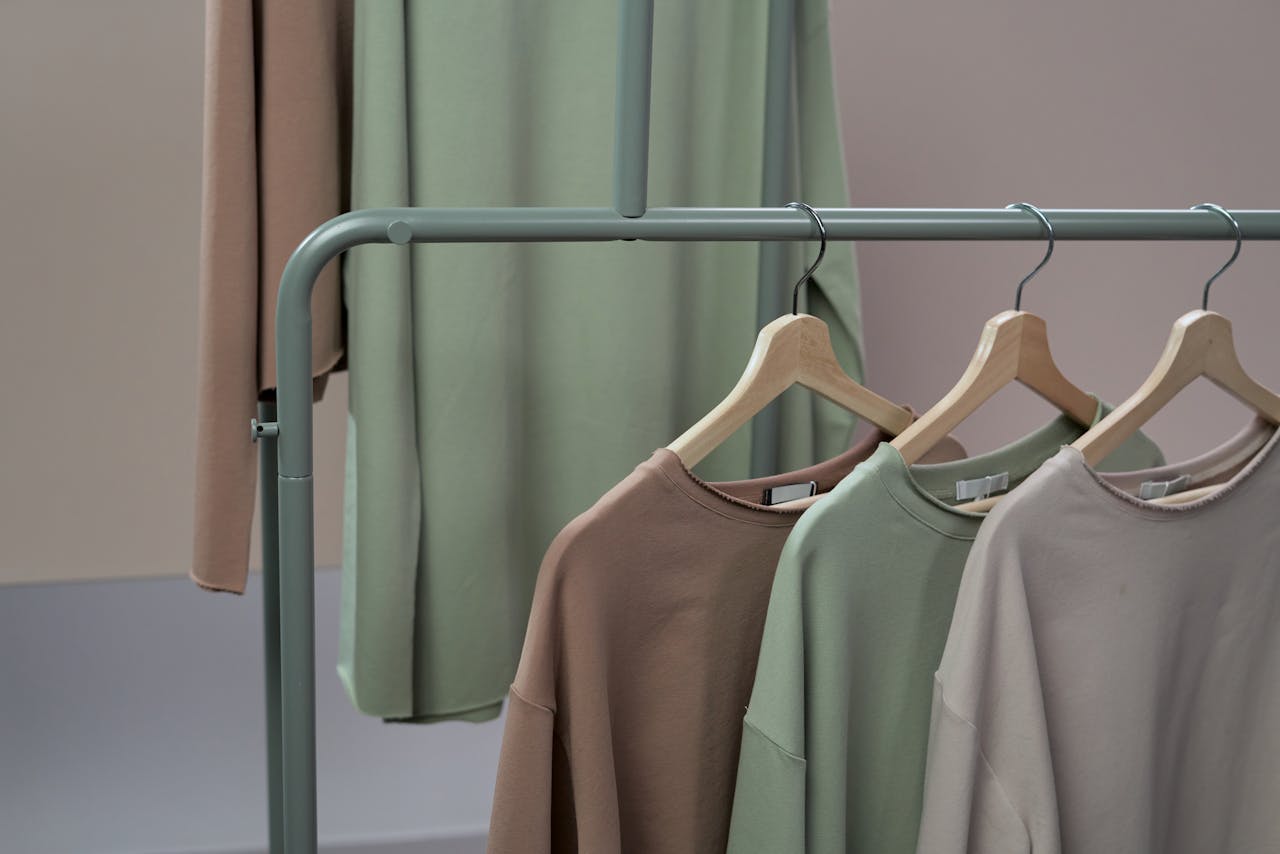 services-04 A stylish display of earth-toned sweaters on hangers in a studio setting.